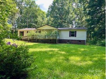 Ranch style home featuring a long front porch and well-maintained yard surrounded by lush trees at 1031 Lester Trl, Iron Station, NC 28080