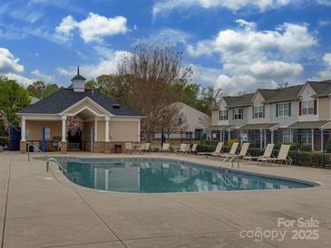 Community pool with lounge chairs, and a covered pavilion, surrounded by well-maintained landscaping at 12550 Mcgrath Dr, Charlotte, NC 28269