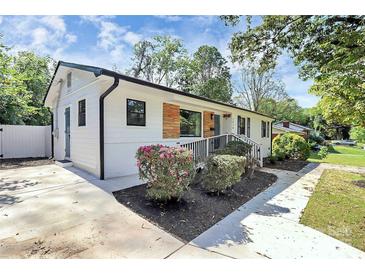 Charming single-story home with white siding, black trim, a well-manicured lawn and beautiful plantings at 2038 Sandhurst Dr, Charlotte, NC 28205