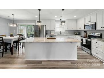 Bright, open kitchen features a large island, stainless steel appliances, and a view of the adjacent dining area at 3018 Corinth Church Rd, Monroe, NC 28112