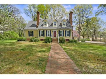 Charming yellow home with blue shutters, brick chimney, and landscaped front yard offers inviting curb appeal at 469 Augusta Dr, Statesville, NC 28625