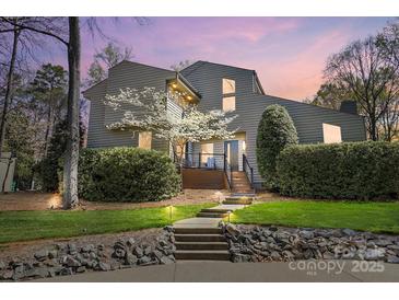 Contemporary home featuring a landscaped front yard, stone accents, and blooming tree, enhanced by outdoor lighting at 6147 Lake Providence Ln, Charlotte, NC 28277