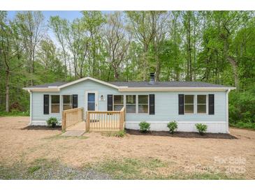 Charming home featuring a light blue exterior, a wooden deck, and black shutters against a backdrop of lush trees at 102 Lansdale Ave, Lincolnton, NC 28092