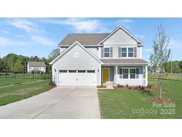 Charming two-story home featuring a welcoming front porch, attached two-car garage, and freshly landscaped yard at 12437 Walker Dr # 89, Stanfield, NC 28163