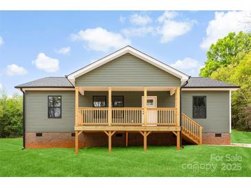 Charming home showcasing a wooden porch, green vinyl siding, and brick foundation accents at 1451 Cherryville Rd, Shelby, NC 28150