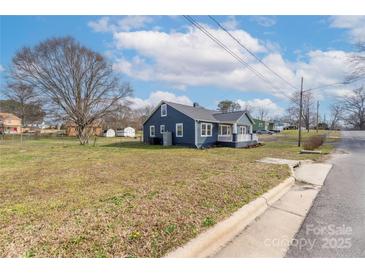 Charming cottage-style home with blue siding and a welcoming front porch on a sunny day at 2230 W 6Th Ave, Gastonia, NC 28052