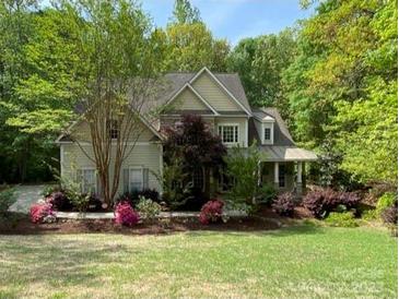 Charming two-story home with manicured lawn and vibrant flowerbeds, surrounded by lush trees at 6108 Mcilwaine Rd, Huntersville, NC 28078