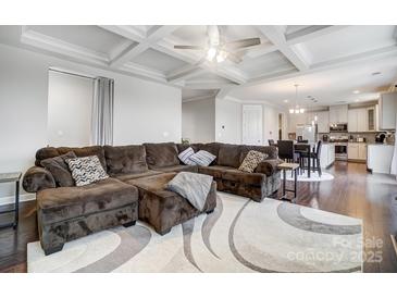 Open concept living room featuring coffered ceilings and a modern kitchen in the background at 10161 Castlebrooke Dr, Concord, NC 28027