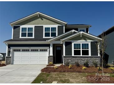 Charming two-story home featuring a two-car garage, stone accents, and a well-maintained lawn at 1440 Mccollum St, Monroe, NC 28112