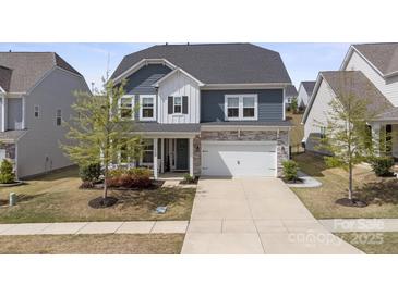 Charming two-story home featuring stone accents, a two-car garage, manicured lawn, and covered porch entry at 15126 Shallow Ridge Rd, Charlotte, NC 28278