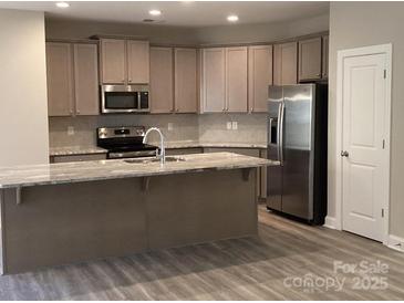 Well-lit kitchen features stainless steel appliances and granite countertops for modern cooking at 5126 Rocky River Crossing Rd, Harrisburg, NC 28075