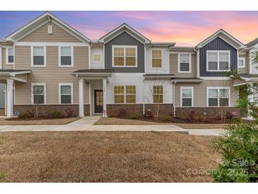 Charming townhome featuring diverse siding and brick accents against a backdrop of a beautiful sunset at 9654 Old Garden Cir, Gastonia, NC 28056