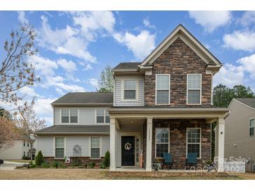 Charming two-story home featuring stone accents, a welcoming front porch, and manicured landscaping at 15324 Colonial Park Dr, Huntersville, NC 28078