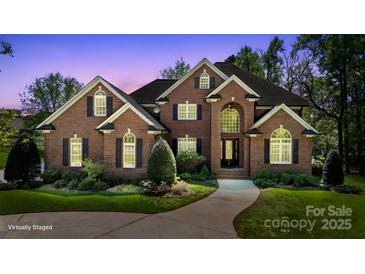 Stunning brick home with manicured lawn, lush landscaping, and a winding walkway to the front door at 2840 Wheatfield Ct, Lincolnton, NC 28092