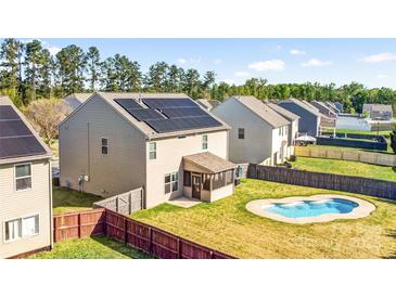 A sunny backyard features a kidney-shaped pool, a small screened porch, solar panels, and fenced yard for outdoor enjoyment at 3010 Berry Creek Rd, Charlotte, NC 28214