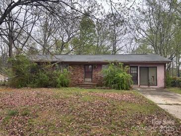 Single story brick home with covered front entrance and attached garage sits on a large wooded lot at 307 Brook St, Salisbury, NC 28146