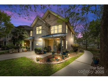 Charming two-story townhome featuring well-lit exterior, landscaped yard, and inviting front porch at twilight at 3414 Chagall Ct, Charlotte, NC 28205