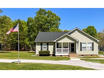 Charming single-story home with a well-maintained lawn, American flag and a gravel driveway at 4285 Palmer Lloyd Rd, Lancaster, SC 29720