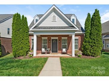 Charming brick home featuring a cozy front porch with seating and meticulously maintained landscaping at 4303 Patriots Hill Rd, Mint Hill, NC 28227