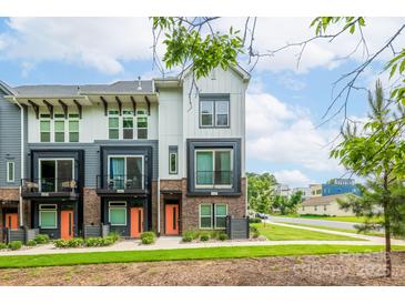 Modern townhome with a brick facade, black framed windows, and a vibrant orange front door at 648 W End Dr, Charlotte, NC 28208