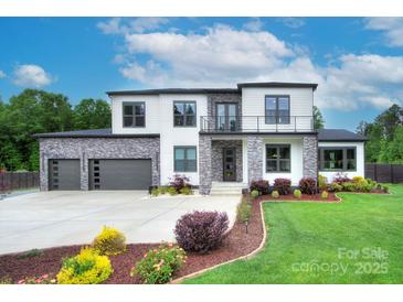 Stunning two-story modern home with stone accents, black framed windows, landscaped yard, and three-car garage at 7005 W Duncan Rd, Indian Trail, NC 28079