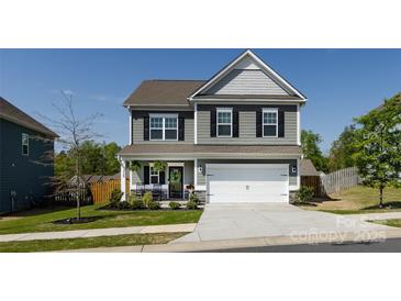 Charming two-story home with a covered front porch, attached two-car garage, and manicured landscaping at 325 Crandon Rd, Mount Holly, NC 28120