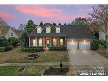 Charming brick home featuring a manicured lawn, dormer windows, and an attached two-car garage at sunset at 331 Miners Cove Way, Fort Mill, SC 29708