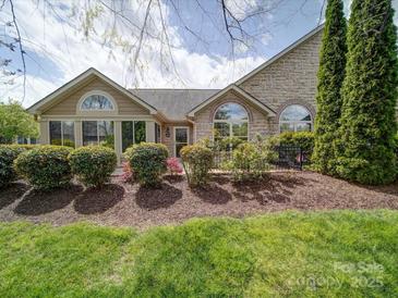 Charming stone home with manicured landscaping and mature trees, creating inviting curb appeal at 4754 Polo Gate Blvd, Charlotte, NC 28216