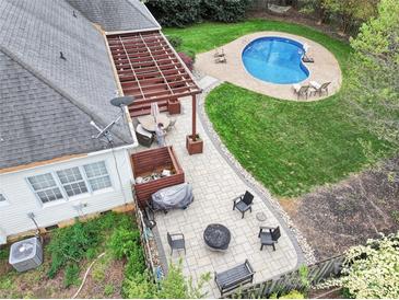 Aerial view of backyard with a patio, pergola, fire pit, and kidney-shaped pool with ample green space at 10609 Washam Potts Rd, Cornelius, NC 28031