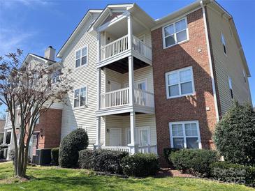 Multi-story condo building with brick and siding, showcasing balconies and landscaped grounds on a sunny day at 10720 Hill Point Ct, Charlotte, NC 28262