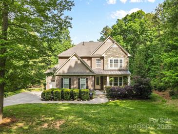 Charming two-story home with a stone and brick facade, lush landscaping, and a well-manicured lawn at 1320 Huntcliff Dr, Waxhaw, NC 28173