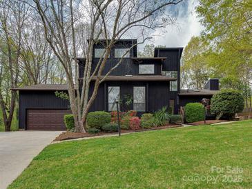 Modern two-story home with unique architectural design, a well-manicured lawn, and mature trees at 1437 Jules Ct, Charlotte, NC 28226