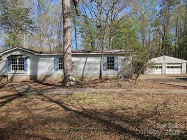 Charming exterior view of a house with blue shuttered windows and overgrown trees at 1586 Brook Ln, Denver, NC 28037