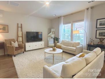 Bright living room boasts neutral decor, plush rug, and lots of natural light through large windows at 314 Olympia Way, York, SC 29745