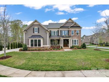 Charming two-story home featuring a beautifully landscaped yard with a mix of stone and shingle siding at 400 Eden Hollow Ln, Weddington, NC 28104