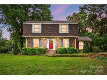 Charming brick home with lush landscaping, red door, and a well-manicured lawn, creating inviting curb appeal at 819 Old Dutch W Rd, Indian Trail, NC 28079