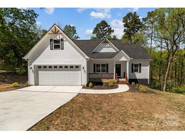 Charming home featuring a white exterior, covered porch, attached garage, and well-manicured lawn at 869 Kathryn Se Dr, Concord, NC 28025
