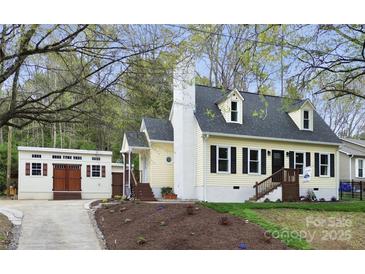 Charming yellow home with a white chimney, complemented by a detached garage and beautifully landscaped front yard at 110 Shamrock Ne St, Concord, NC 28025