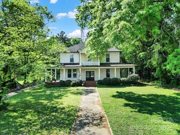 Charming two-story home with inviting front porch and well-manicured lawn, nestled amongst mature trees at 407 Chesterfield Ave, Lancaster, SC 29720