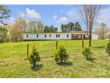 Charming single-story home with a brick accent, surrounded by a lush green lawn and a delicate metal fence at 1975 Old Wilkesboro Rd, Taylorsville, NC 28681