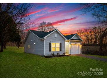 Charming single-story home with gray siding, black shutters and beautiful landscaping at 212 S Columbia St, Gastonia, NC 28054