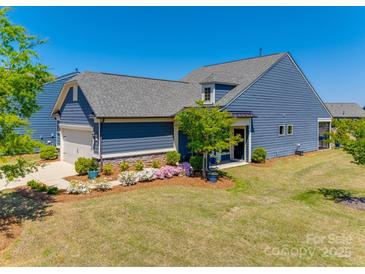 Beautiful blue home featuring a two-car garage, manicured lawn, and stone accents at 4502 Middlebury Ln, Fort Mill, SC 29715