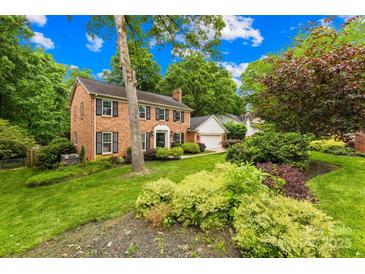 Traditional brick home with black shutters, well-manicured lawn and lush landscaping at 6744 Wheeler Dr, Charlotte, NC 28211