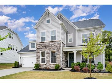 Charming two-story home with stone accents, a well-manicured lawn, and a welcoming front porch for relaxation at 15230 Ravenall Dr, Huntersville, NC 28078