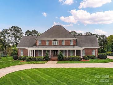 Stately brick home featuring a manicured lawn and covered porch with elegant columns, perfect for Southern charm at 1902 Windmere Dr, Monroe, NC 28110
