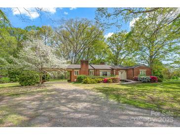 Charming brick home featuring a lush front yard, mature trees, and a convenient carport at 252 Stamey Farm Rd, Statesville, NC 28677
