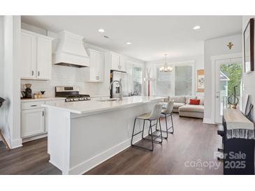 Bright, open kitchen features white cabinets, subway tile backsplash, stainless steel appliances, and a view to the living room at 562 Amalfi Dr, Davidson, NC 28036