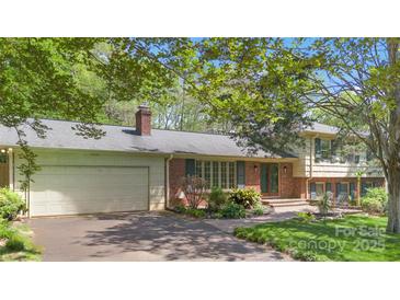 Charming brick home with an attached two-car garage, beautiful landscaping, and a well-manicured front yard at 6921 Thermal Rd, Charlotte, NC 28211