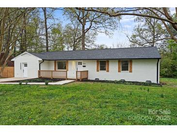 Charming single-story home with a white brick exterior, dark roof, and inviting front porch at 908 Woodside Dr, Kings Mountain, NC 28086