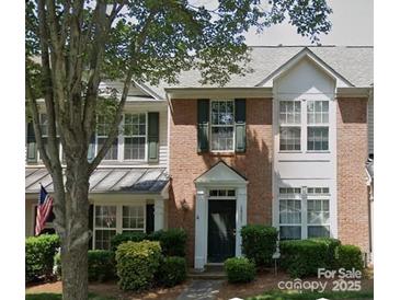 Charming two-story townhouse featuring a brick facade, green shutters, and well-maintained landscaping at 19057 Coachmans Trce, Cornelius, NC 28031
